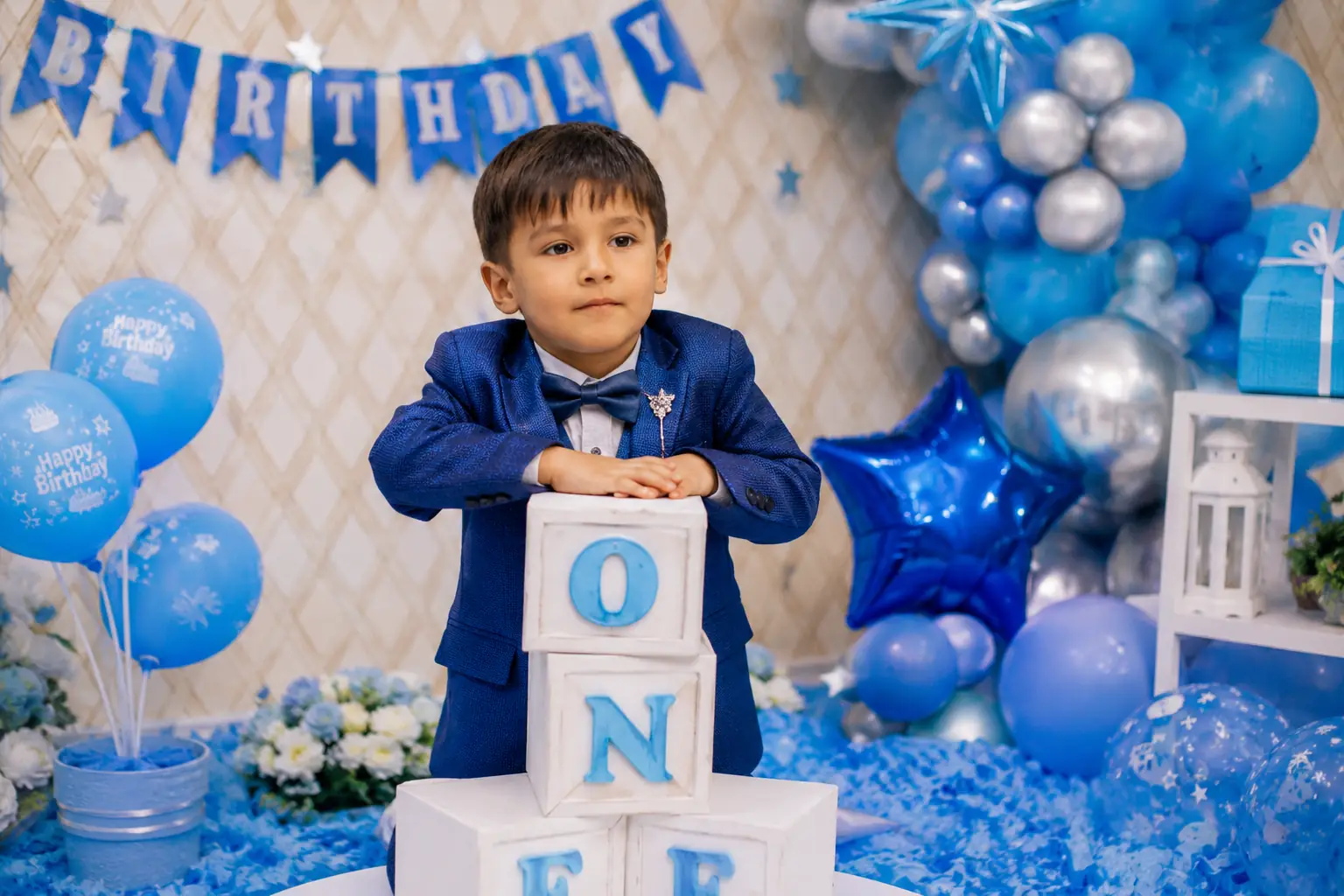 Best Birthday Photographer in Delhi capturing a blue-themed first birthday celebration with baby boy, family, cake and premium birthday decorations